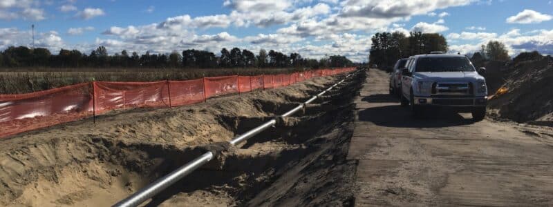 View of underground pipeline exposed in a shallow trench with a blue sky in the background